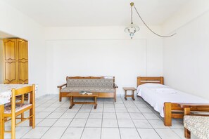 A room with a wooden sofa, a small table, a bed, and a wardrobe. - Yiannis (Karpathos)