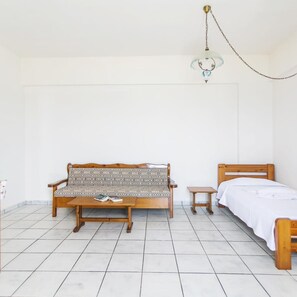 Quarto com sofá de madeira, uma mesa pequena, uma cama e luminária pendente.