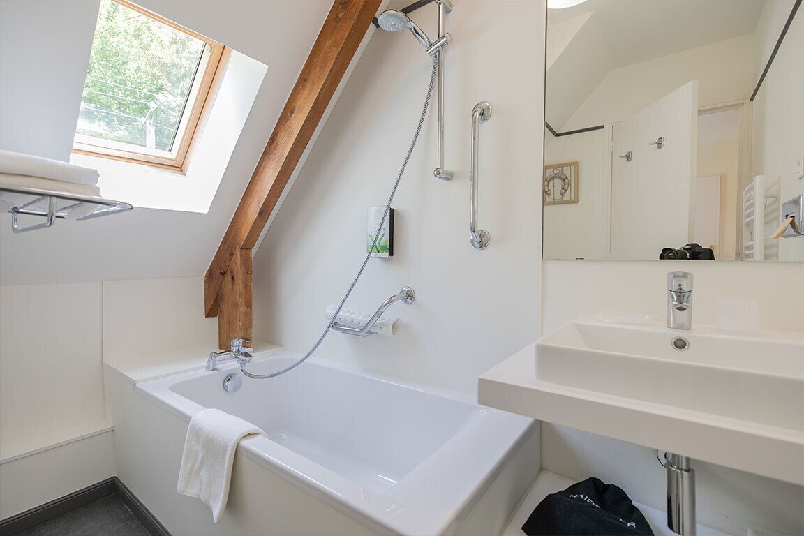 Un baño moderno con una bañera independiente, un cabezal de ducha, un lavabo y un espejo.
