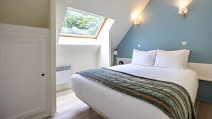 Une chambre à coucher avec un lit, une lucarne et un luminaire fixé au mur.