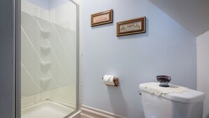 A bathroom with a glass shower enclosure, a toilet with a decorative bowl, and two framed pictures on the wall. - Les Matins de Victoria (Waterloo)