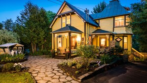 A two-story house with a porch, a stone pathway, and a small garden. - Les Matins de Victoria (Waterloo)