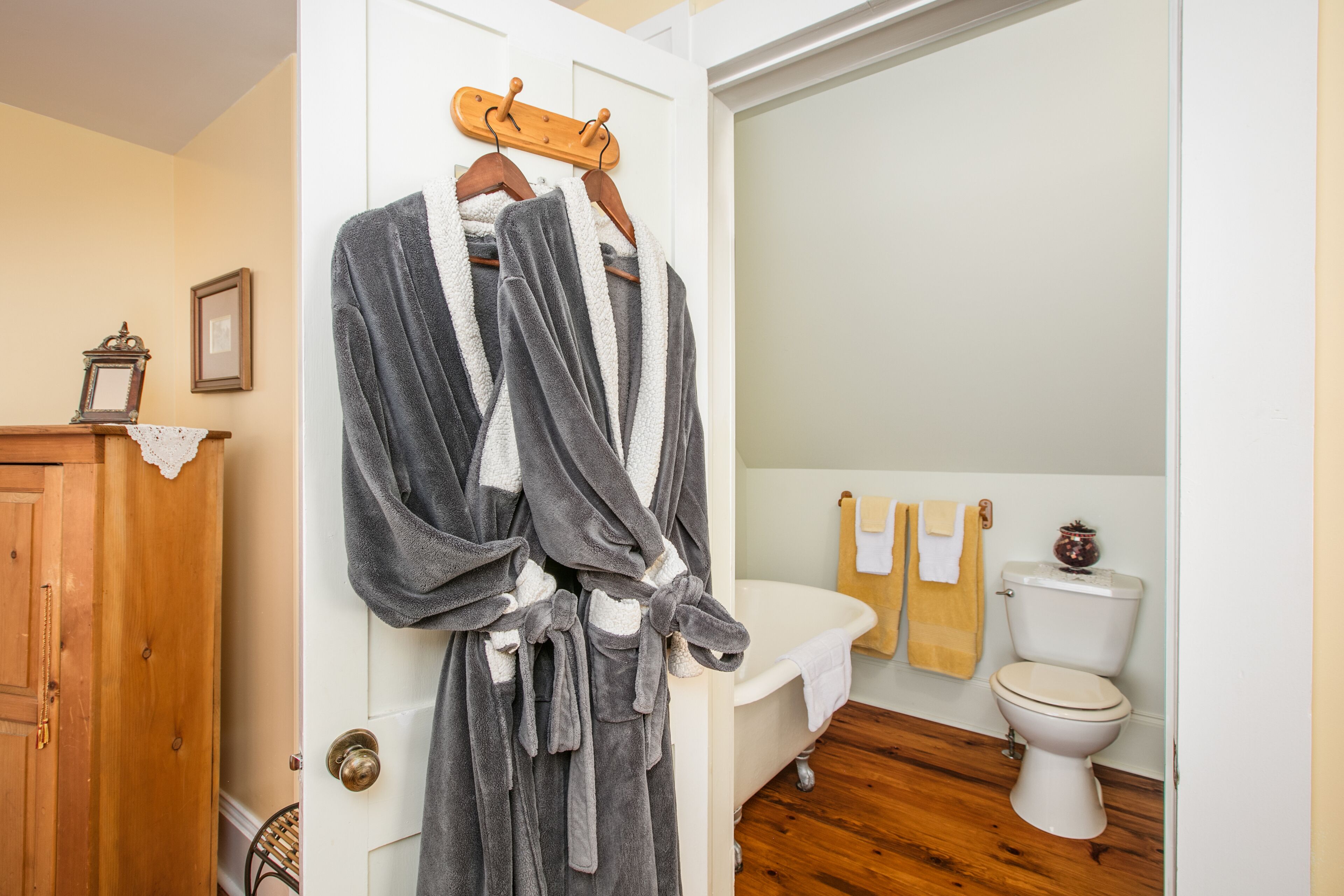 A bathroom with a bathtub, toilet, and wooden floor.