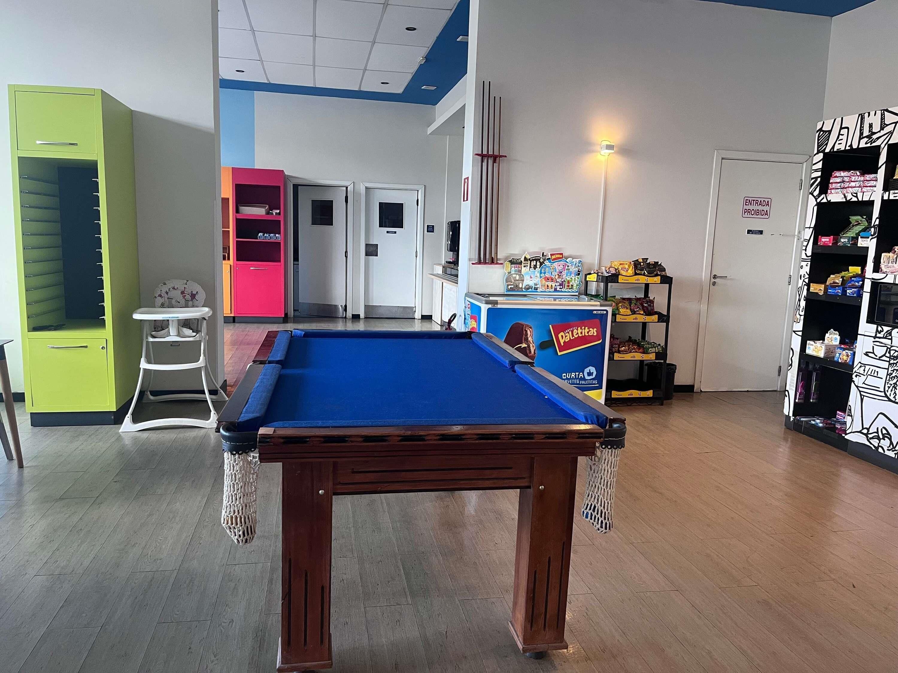 A pool table in a room with a green cabinet, a pink cabinet, and a white door with a sign.