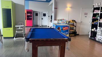 A pool table in a room with a green cabinet, a pink cabinet, and a white door with a sign.