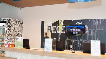 A hotel reception area with an online check-in sign, a large wall with abstract art, and a television displaying a building.