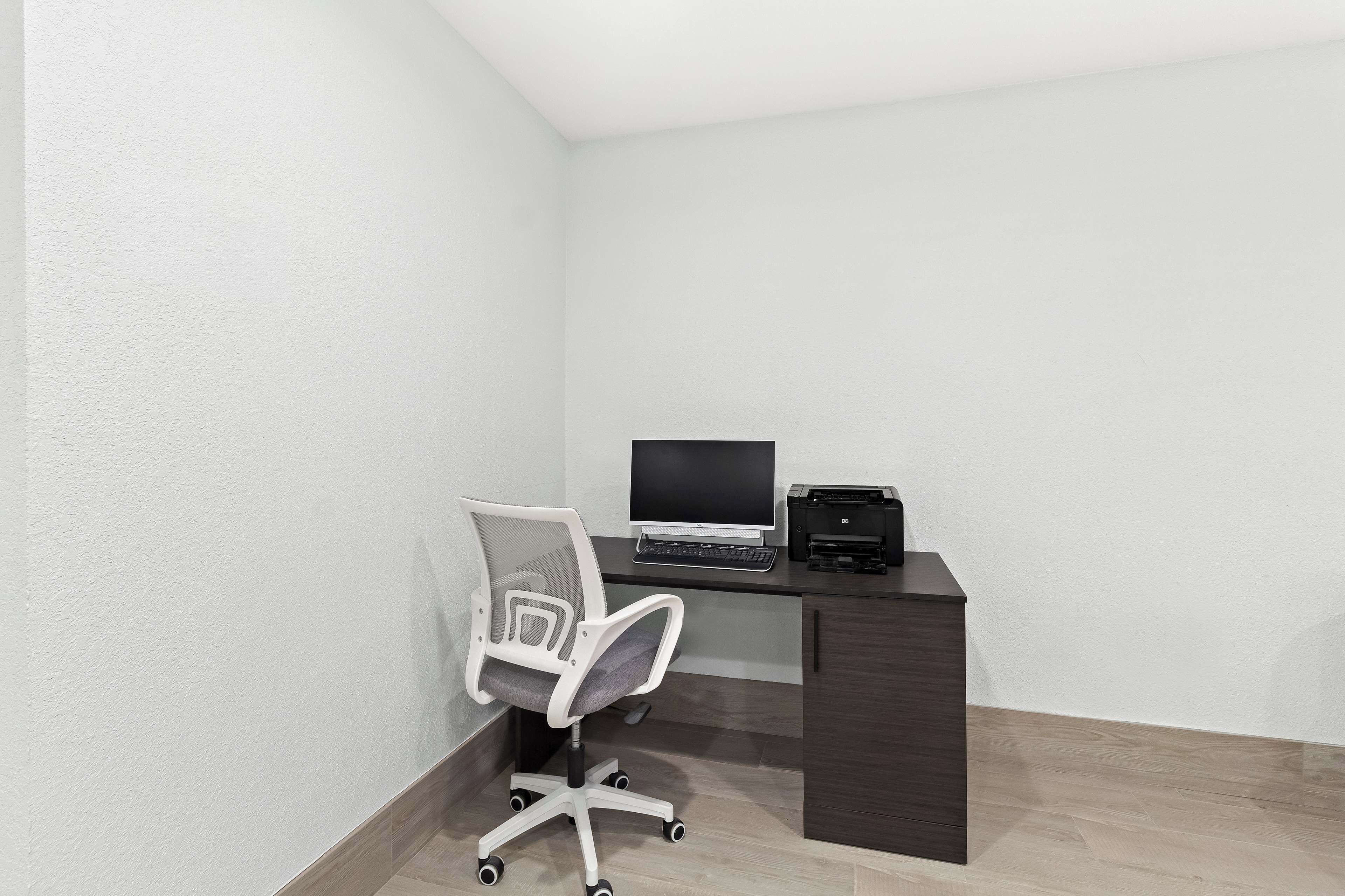 Un petit bureau comprenant un bureau, une chaise, un ordinateur et une imprimante.