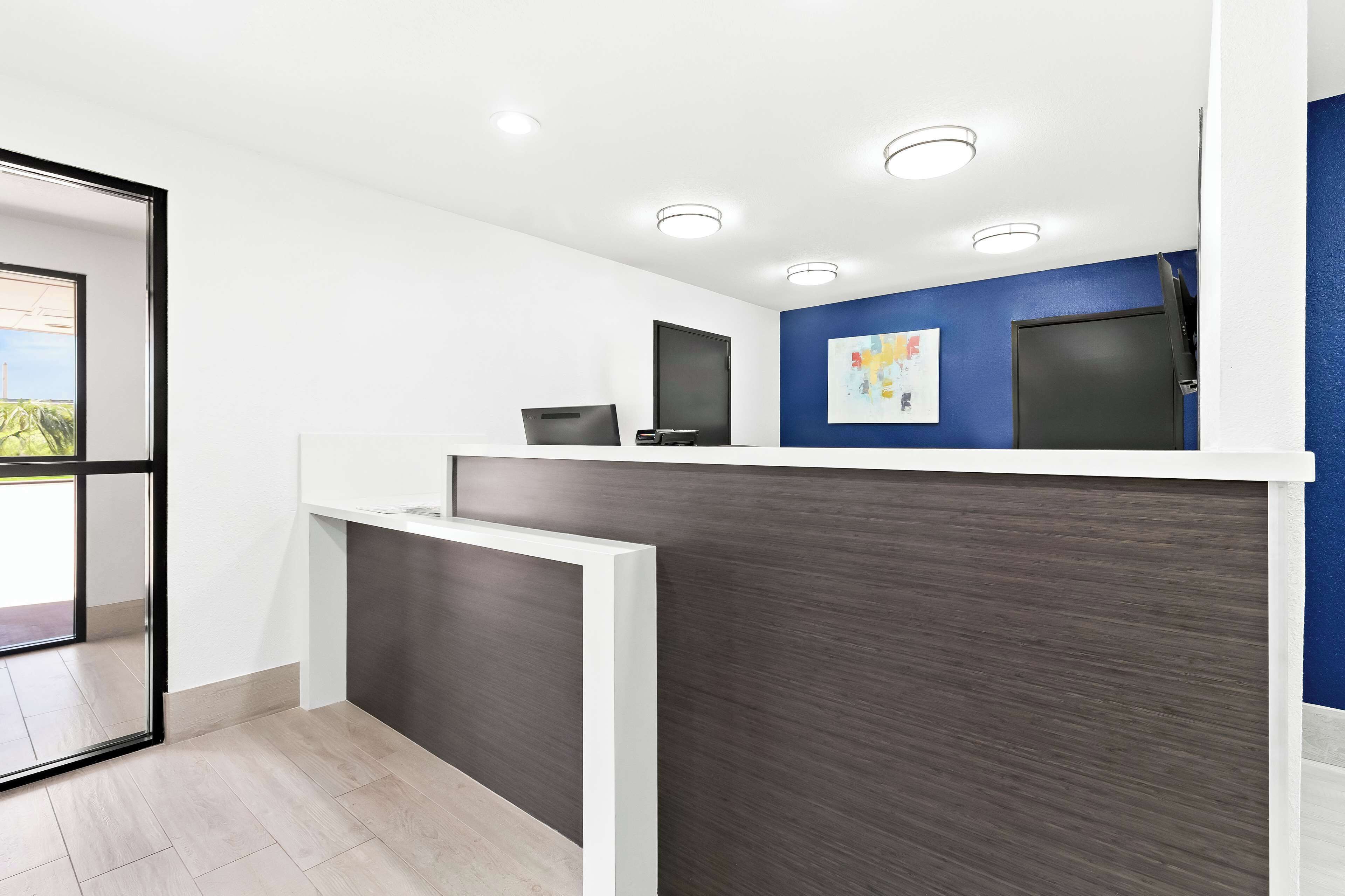 Een receptiegedeelte met een modern design, met een donker houten receptiebalie, witte wanden en een blauwe accentmuur.