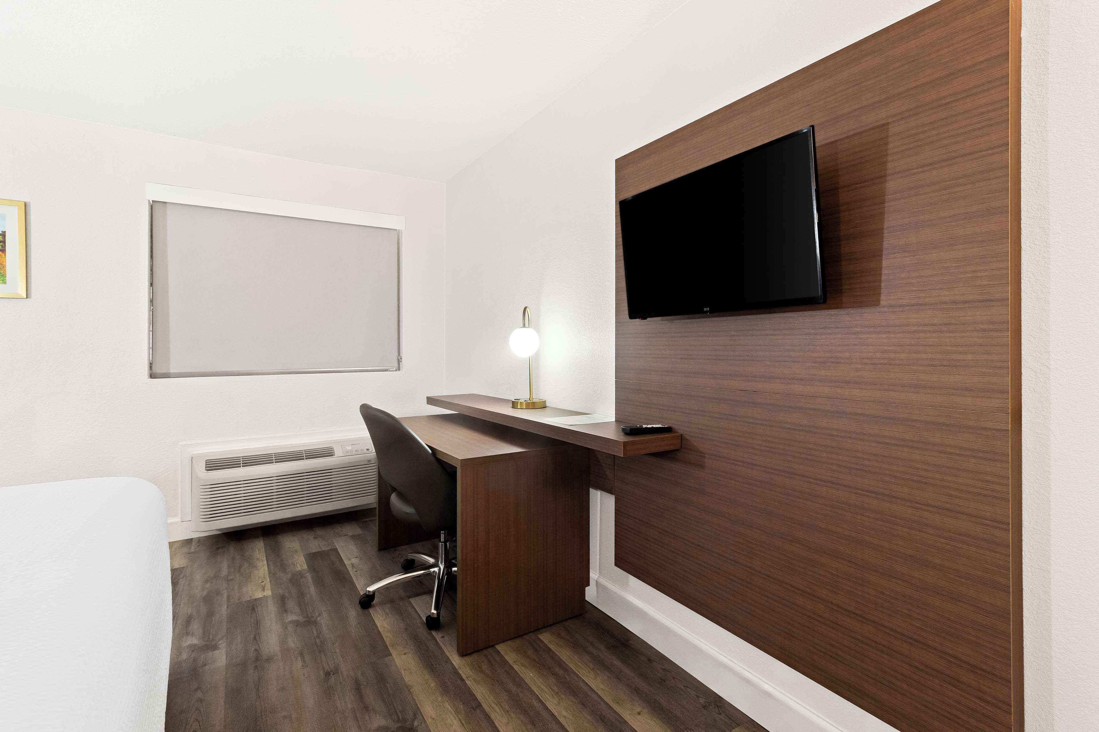 Un espacio de oficina moderno con un escritorio, una silla y un televisor montado.