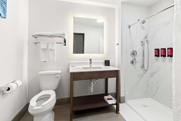A modern bathroom with a toilet, sink, mirror, and shower.