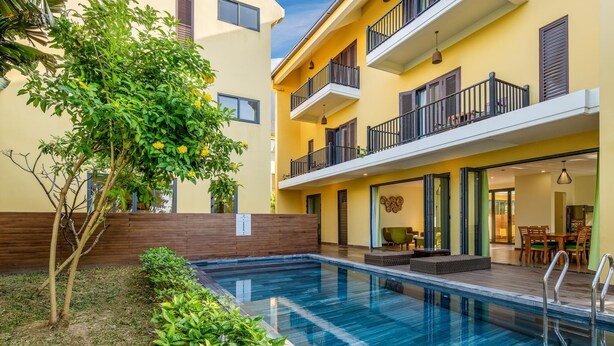 A modern building with a swimming pool, balconies, and a dining area. - Hoa Co Villas (Da Nang)