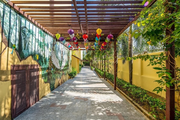 Un pasillo con techo de madera, coloridos faroles colgantes y un mural en la pared izquierda.