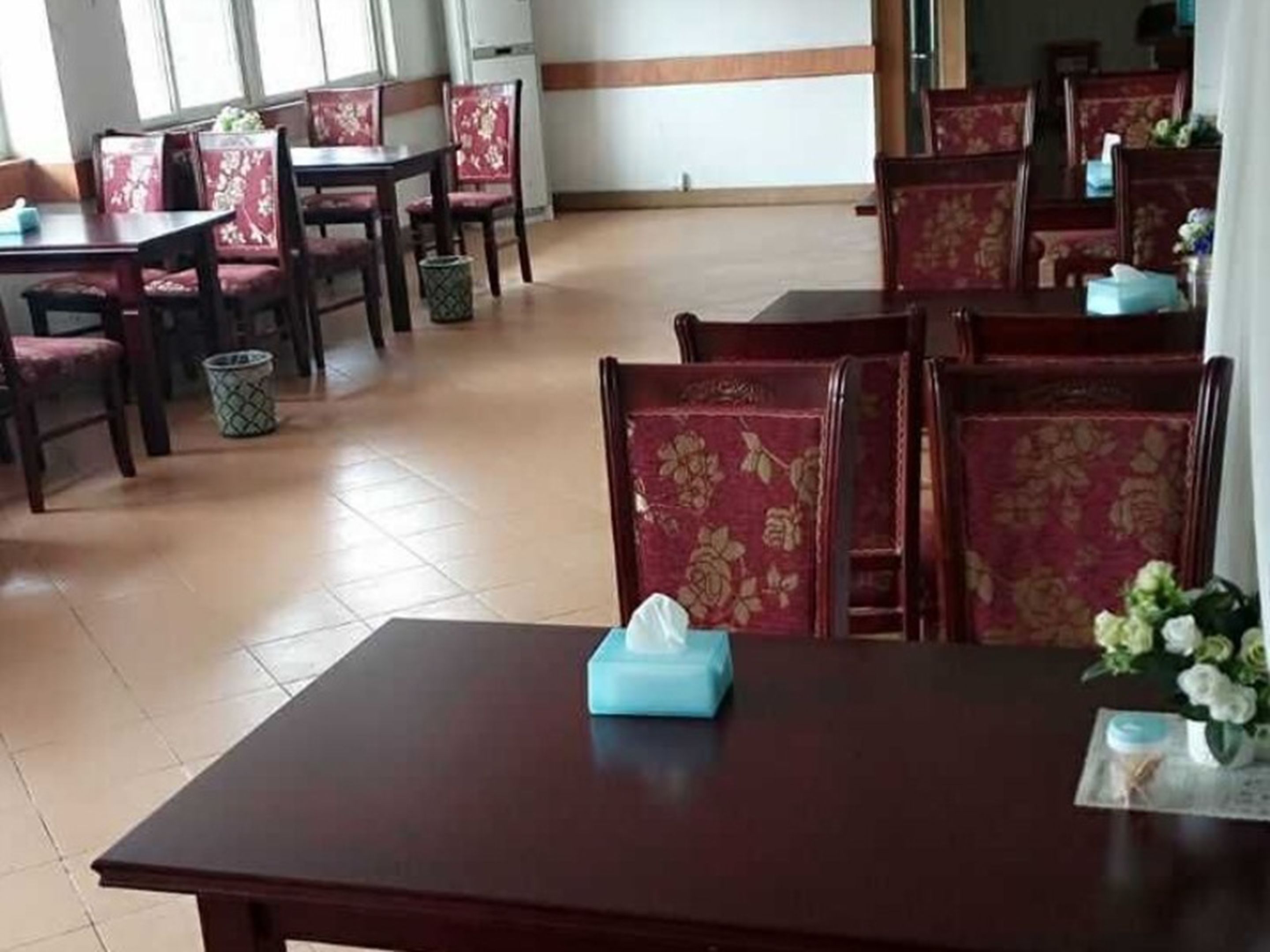 Un coin repas avec des chaises à revêtement rouge et une table sur laquelle se trouve une boîte de mouchoirs.