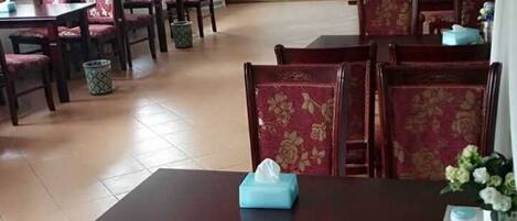 Un coin repas avec des chaises à revêtement rouge et une table sur laquelle se trouve une boîte de mouchoirs.