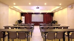 A conference room with multiple tables and chairs, a large screen, and a projector.