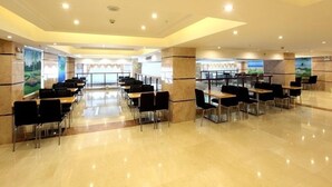 A spacious conference room with multiple tables and chairs, large windows, and a polished floor.