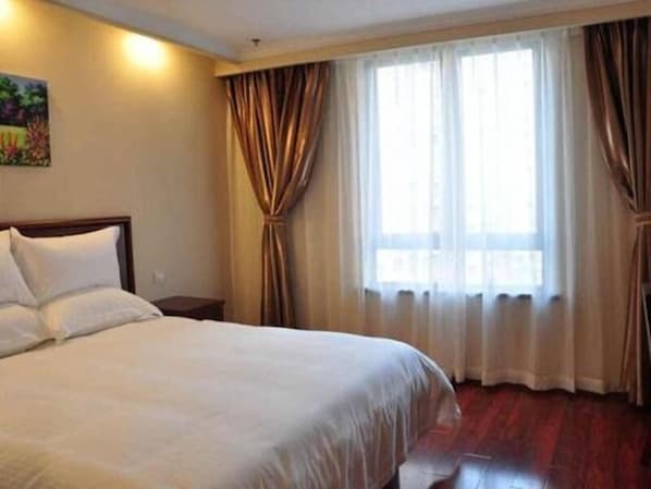A hotel room with a large bed, a nightstand, and a window with curtains.