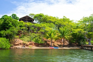 Une maison au bord d’un lac, avec un quai et un bateau rouge.