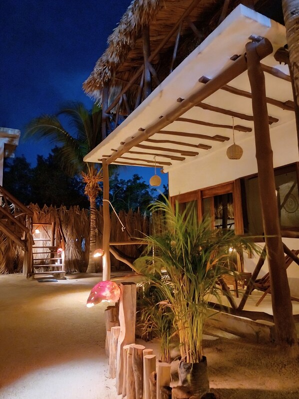 A wooden structure with a thatched roof, a covered seating area, and a potted plant. - Casa Sofia Holbox (Isla Holbox)