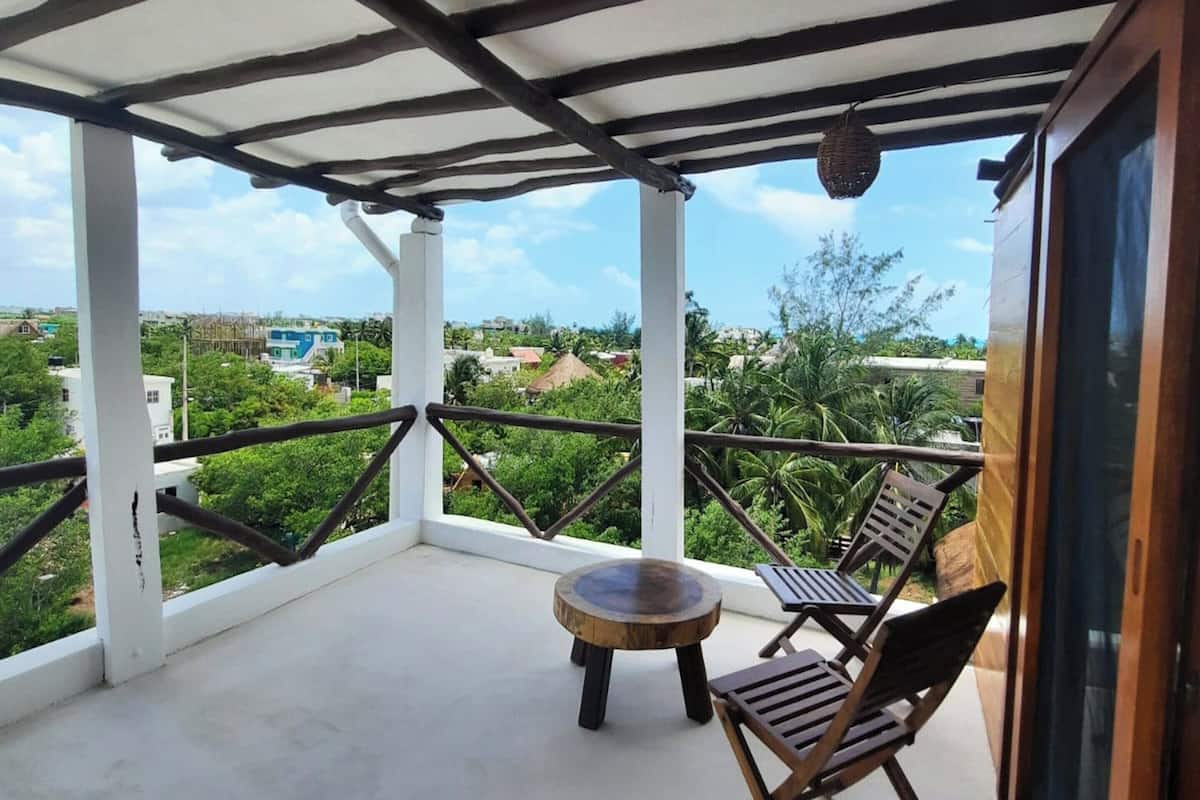 Un balcón con una mesa y dos sillas, con vistas a una zona residencial con casas y vegetación.