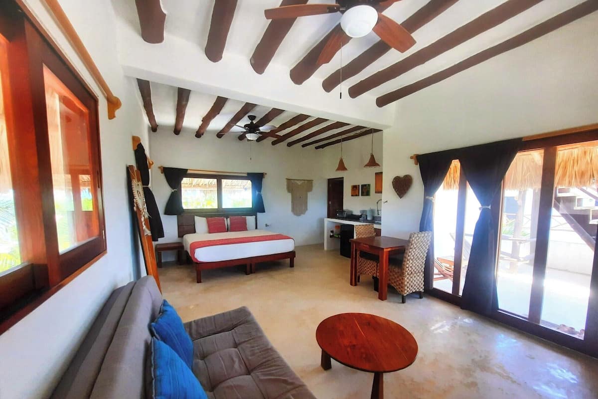 Una habitación amplia con una cama, un sofá, una mesa de comedor y un ventilador de techo.