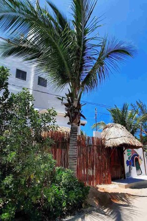 A white building with a thatched-roof structure in front. - Casa Sofia Holbox (Isla Holbox)