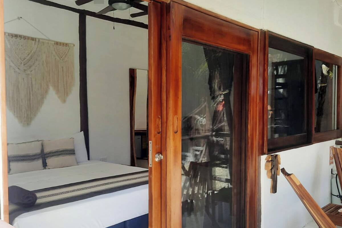 Un dormitorio con una cama, una puerta de madera y vistas al exterior.