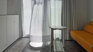 Une chambre moderne avec une armoire blanche, une petite table ronde et un canapé orange vif.
