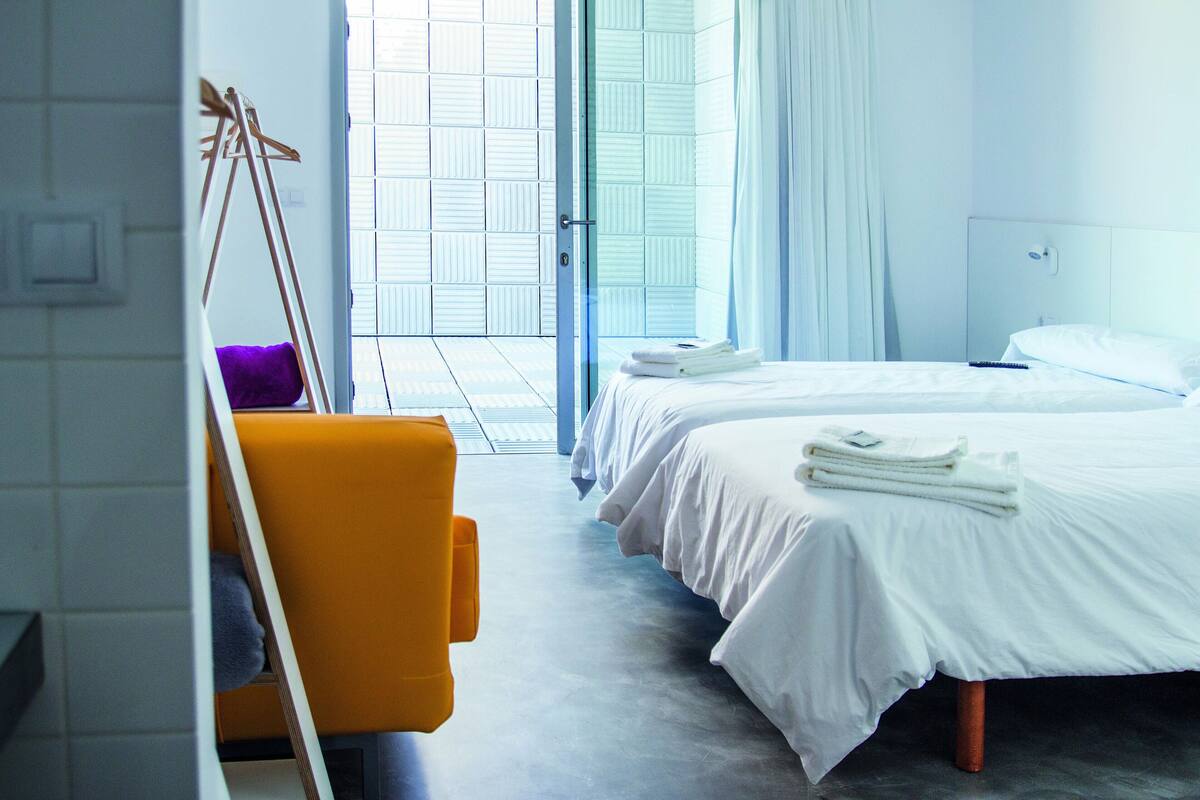 Ein Hotelzimmer mit zwei Betten, einem großen Fenster und Blick nach draußen.