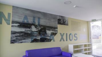 A reception area with a large wall mural, a purple sofa, a white table, and a bookshelf.