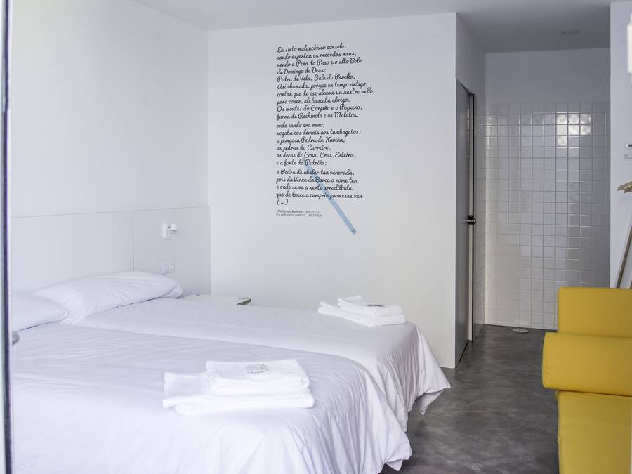 A hotel room with two beds, a yellow chair, and a wall with text.