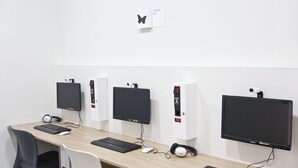 Une salle informatique équipée de quatre postes de travail, chacun comprenant un écran, un clavier et un casque audio.