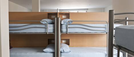 Habitación con literas, dos camas, cada una con almohada y una pequeña estantería.