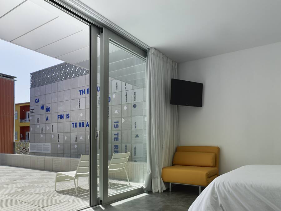 Ein modernes Hotelzimmer mit einer Schiebetür zu einem Außenbereich, einem Bett, einer Couch und einem an der Wand befestigten Fernseher.