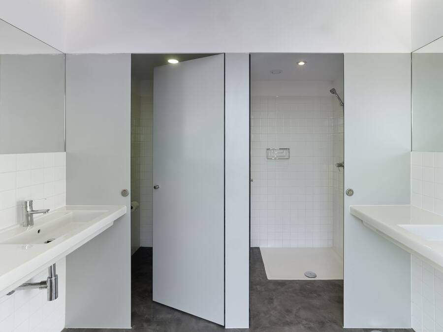 Un baño moderno con un lavamanos blanco, una ducha y un inodoro.