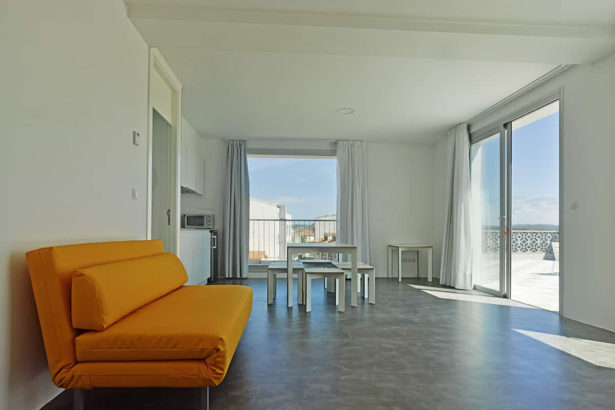 Ein modernes Hotelzimmer mit einer Sitzecke, einem Esstisch und Meerblick.