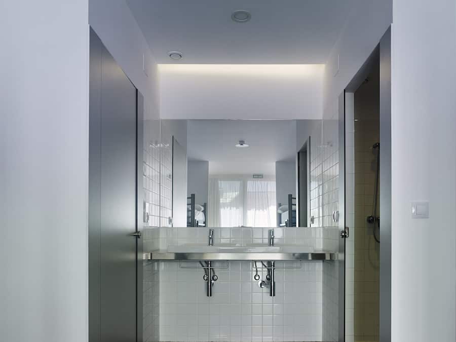 A modern bathroom with a large mirror, two sinks, and a shower.