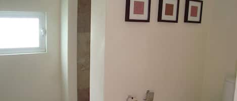 Un baño con inodoro, ducha y tres cuadros en la pared.