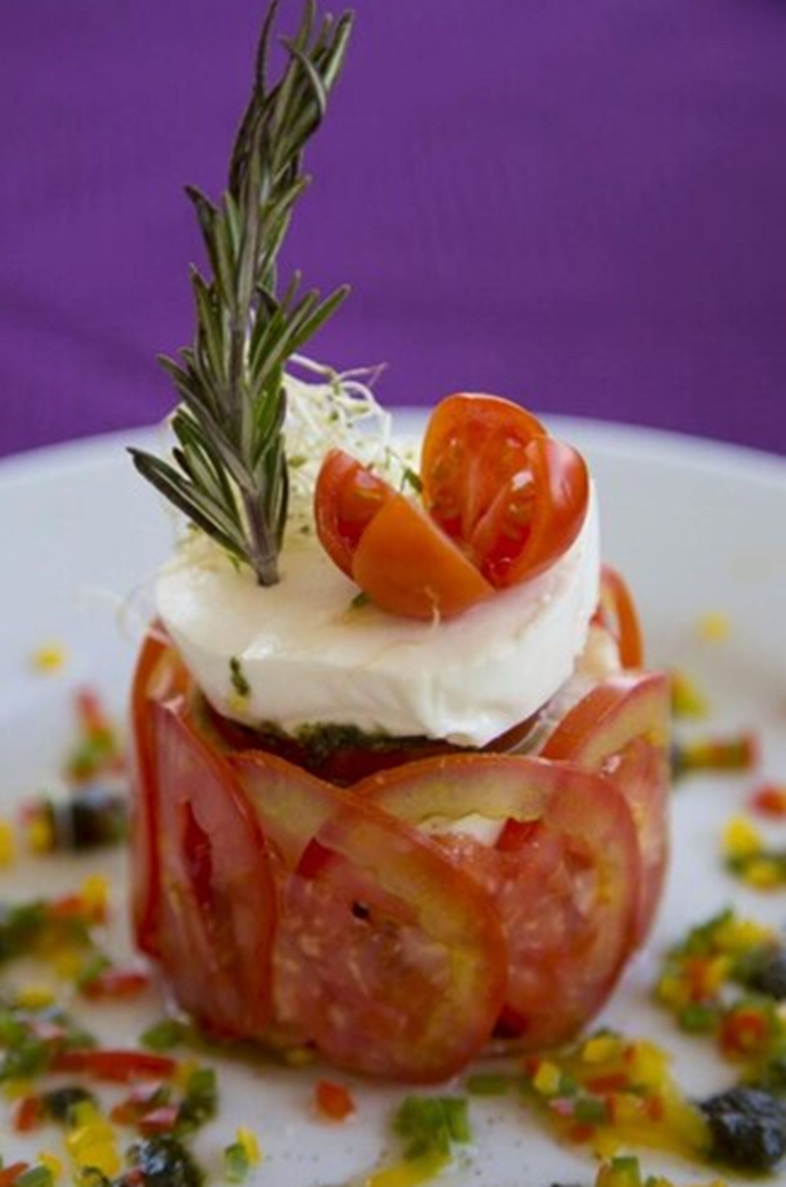 Un plato con salsa de tomate, cubierto de queso y una ramita de romero.