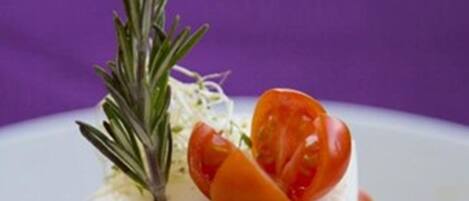 Un plato con salsa de tomate, cubierto de queso y una ramita de romero.