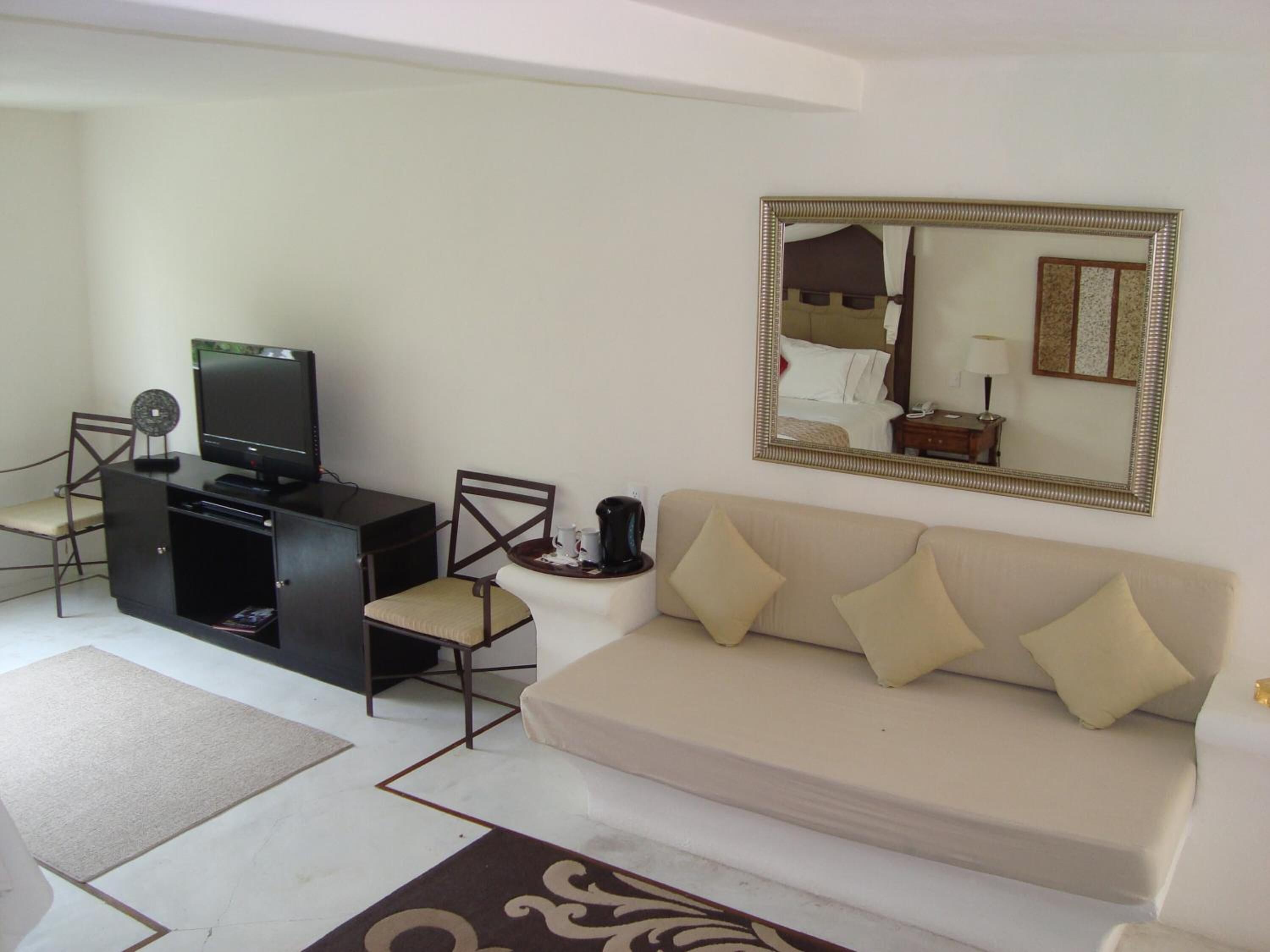 A living room with a sofa, a television, a coffee table, and a mirror.