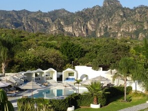 Una piscina al aire libre, sombrillas, sillones reclinables de piscina