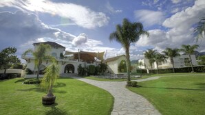 A modern house with a paved pathway leading to the entrance, surrounded by well-maintained lawns and palm trees. - Sitio Sagrado (Tepoztlán)