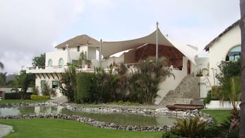 Un resort moderno con una piscina grande, un área exterior techada y una escalera que lleva al edificio principal.
