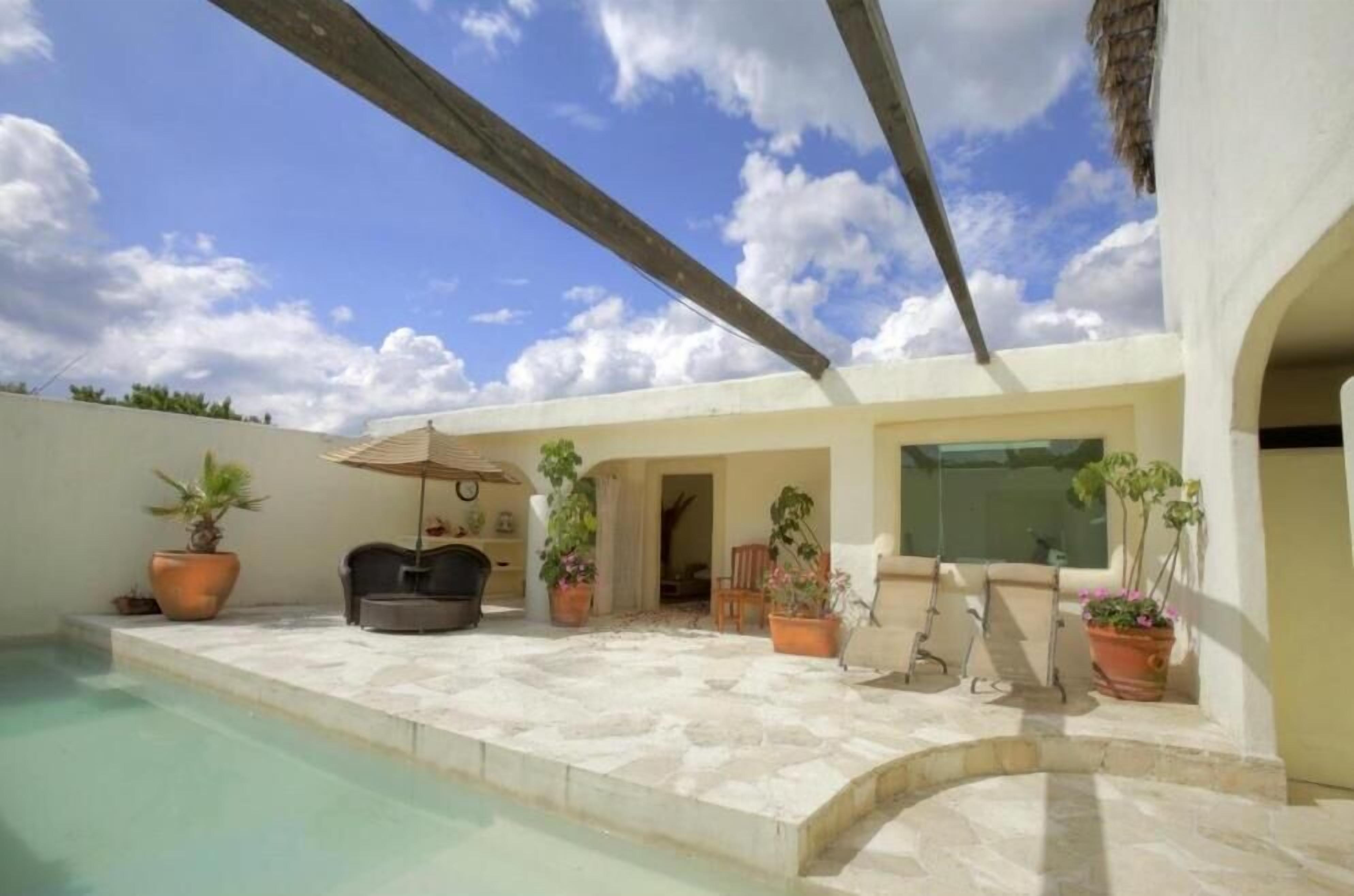 A poolside area with a stone deck, potted plants, and outdoor furniture.