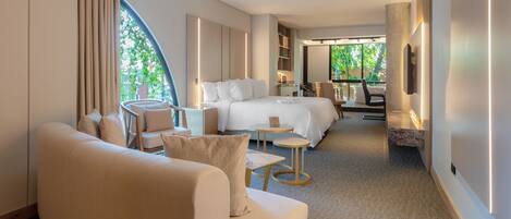 Ein modernes Hotelzimmer mit einem großen Bett, einer Couch, einem kleinen Tisch und einem Fernseher.