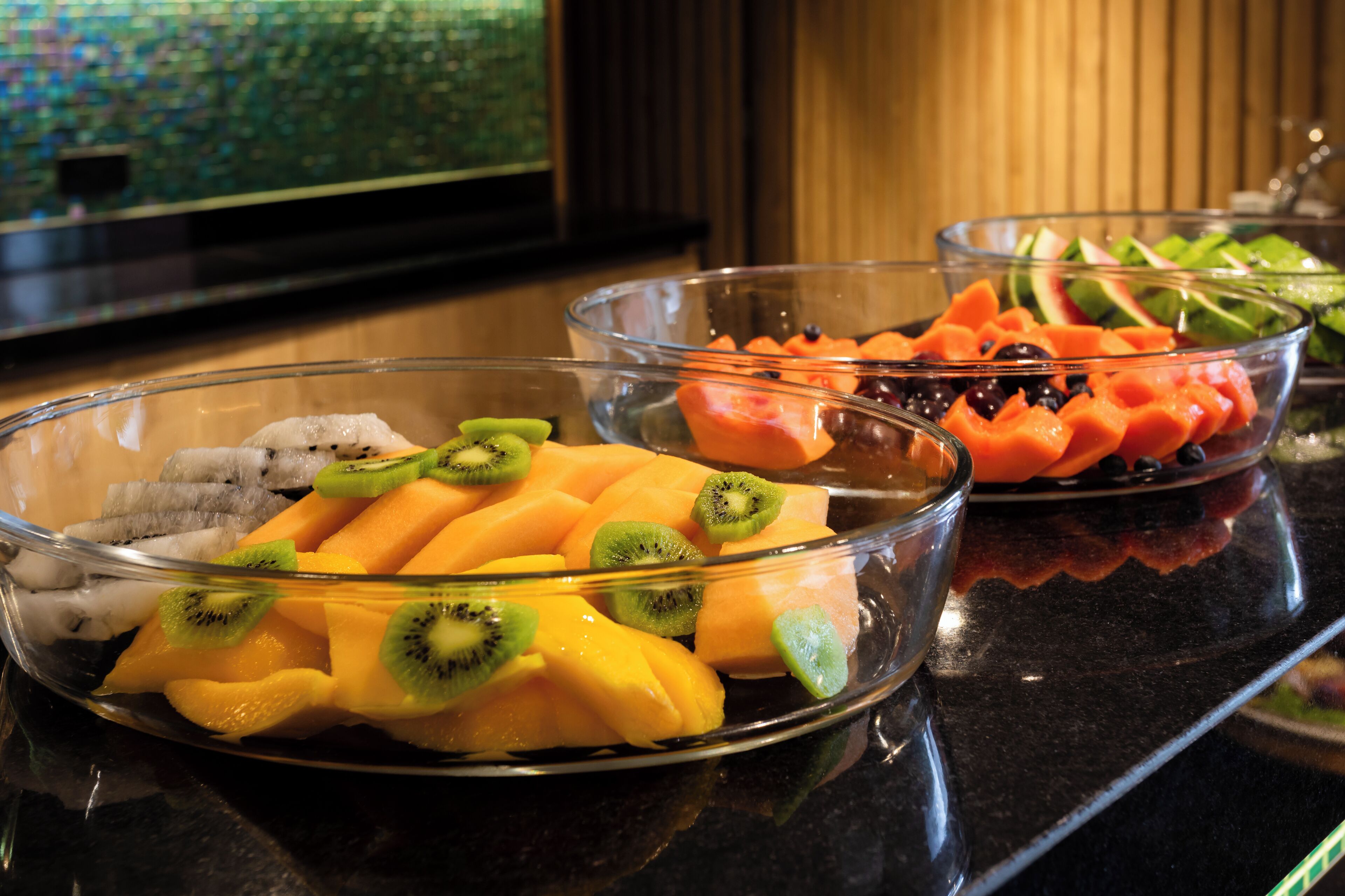 A buffet with various fruits including kiwi, mango, and melon.