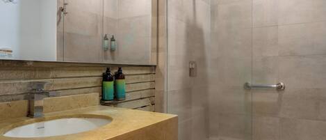 A modern bathroom with a wooden vanity, a white toilet, and a glass-enclosed shower.