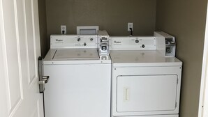 A laundry room with two stacked washers and dryers, a white door, and a light fixture on the ceiling. - Relax Inn of Medford (Medford)