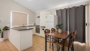 A compact kitchen with a central island, dining table, and chairs. - Karratha Caravan Park (Karratha Industrial Estate)
